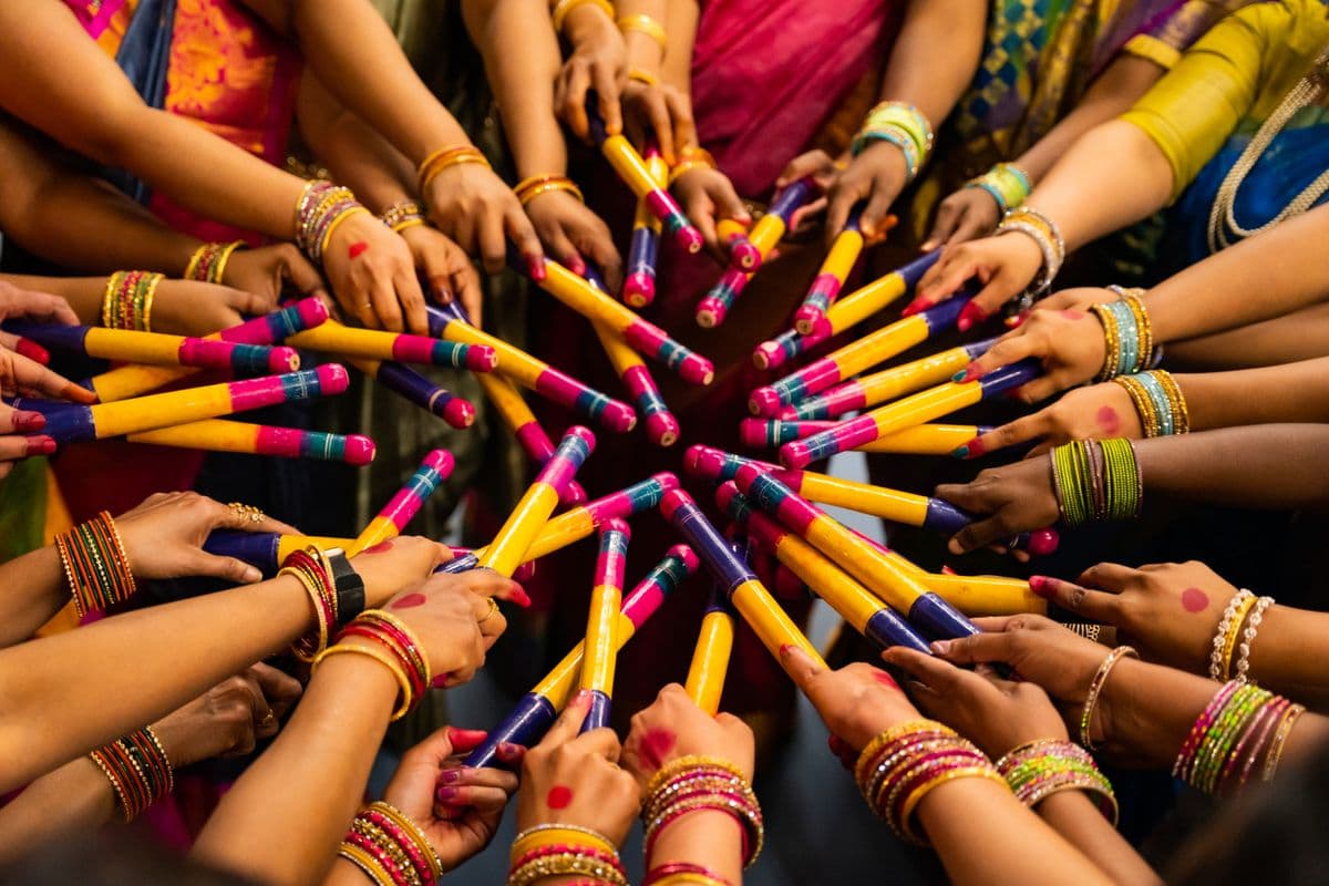 Hands holding dandiya sticks during a Navratri Garba dance